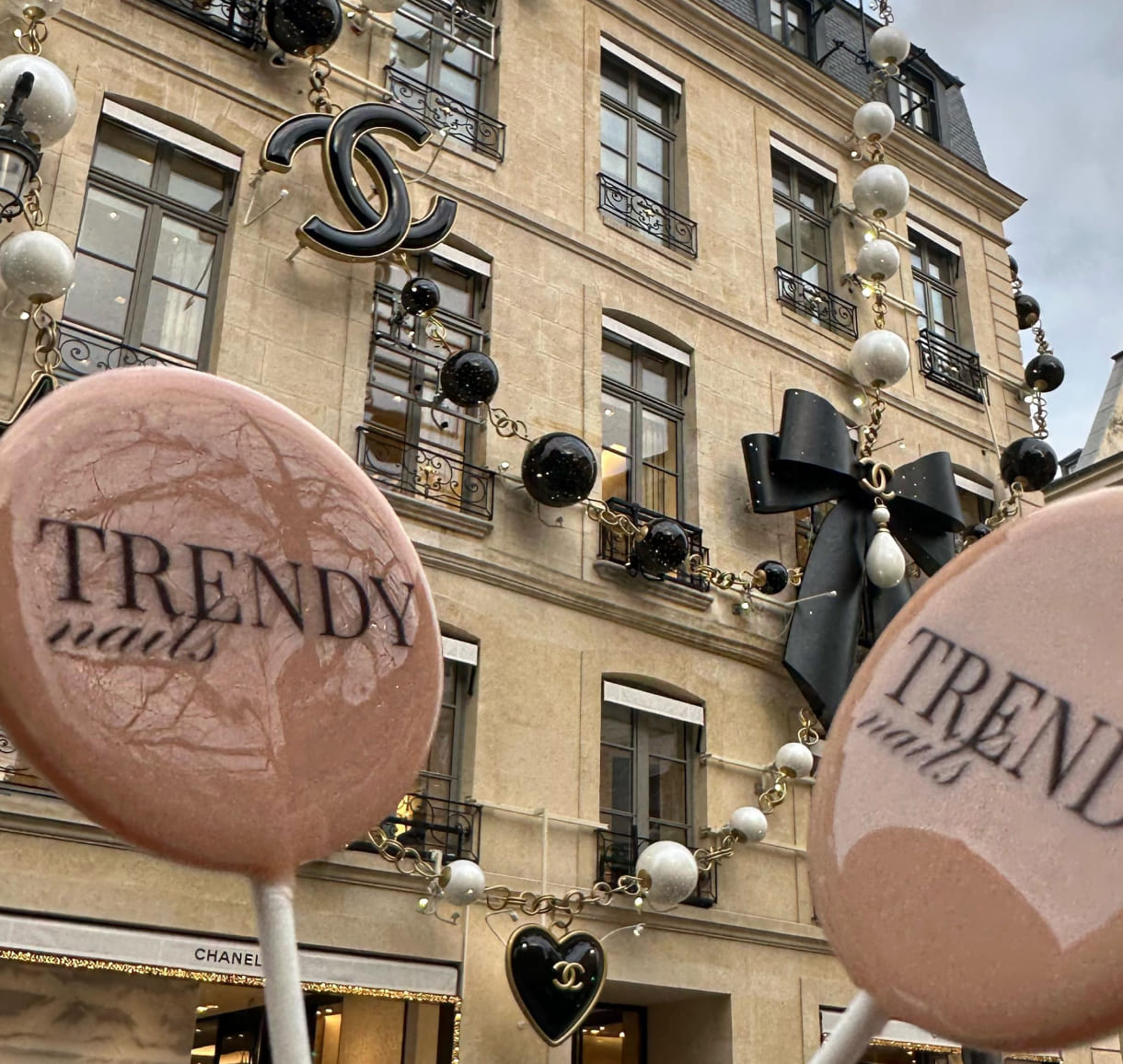 Trendy Nails lollipops in front of a luxury Chanel store with decorative pearls and bows